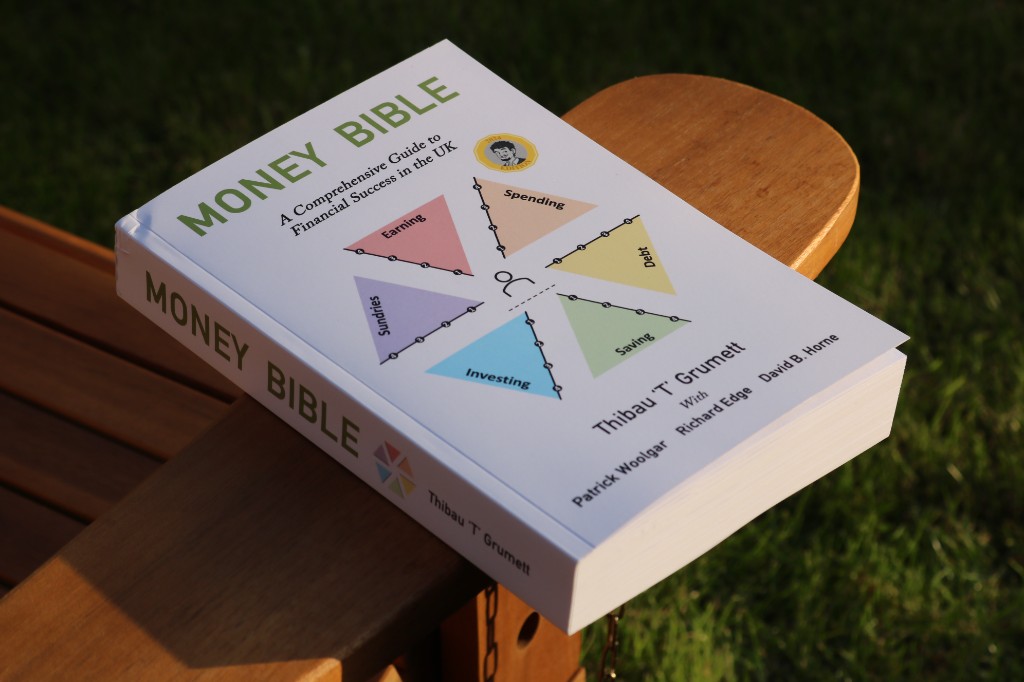 Money Bible paperback resting outdoors on wood